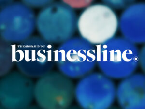 The Hindu Businessline logo over a blurred photo of a top view multi colored oil barrels